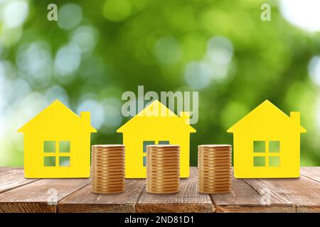 Real estate investing. House models and coins on wooden table Stock Photo