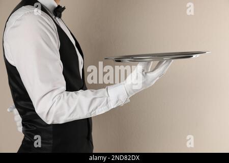 Butler with tray on beige background, closeup Stock Photo