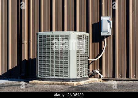 Horizontal shot of a commercial air conditioning unit with electrical box outside a retail shopping center. Stock Photo