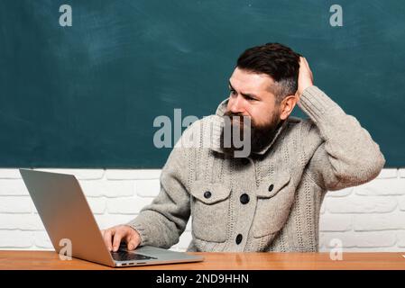 Bearded teacher. Studying at university. Young female student ready to write exam testing. Young teacher near chalkboard in school classroom. Stock Photo