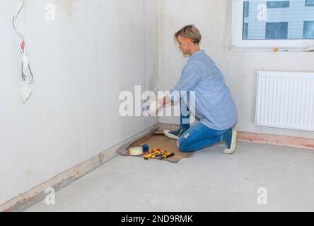 Woman electrician installs sockets in wall of room. Renovation in new apartment. Repair work of home. High quality photo Stock Photo