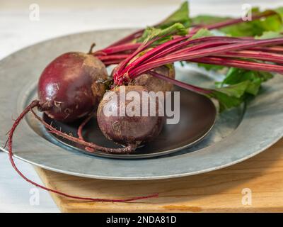 Beets with bright red stems and green leaves ready to be peeled and sliced. Stock Photo