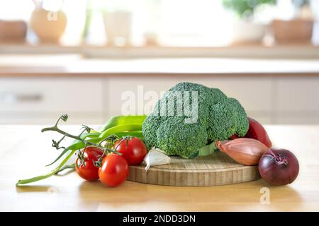 Broccoli and other fresh vegetables on a wooden worktop, preparation for healthy cooking, the blurred modern kitchen in the background, copy space, se Stock Photo