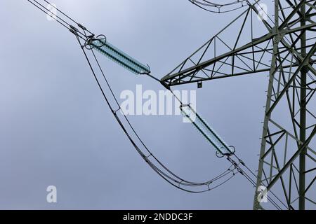 Close-up of insulators on high-voltage pylons against a cloudy sky. High voltage transmission lines Stock Photo