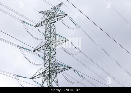 The silhouette of a high-voltage pylon against a completely cloudy sky. Development of high-voltage transmission networks Stock Photo