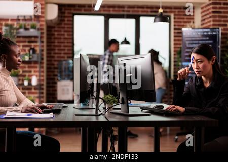 Pensive asian tech programmer working on code development and brainstorming ideas to create html script. Thoughtful Programming engineer thinking about database server in it agency office. Stock Photo