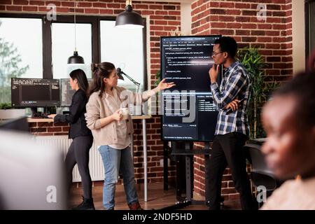 Diverse software developers working on it project for the company network technology, utilizing their expertise in coding systems. Tech enginners javascript code in programming agency office. Stock Photo