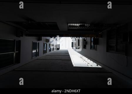 A greyscale low angle shot of the tall building in shadow with sky above Stock Photo