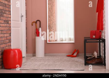 Different pairs of shoes under bench in hall. Storage idea Stock Photo