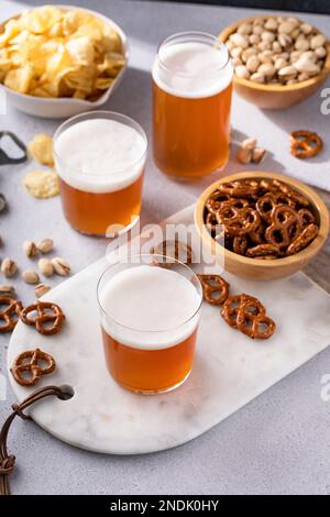 Traditional lager beer in variety of glasses with different snacks on the table on a sunny day Stock Photo
