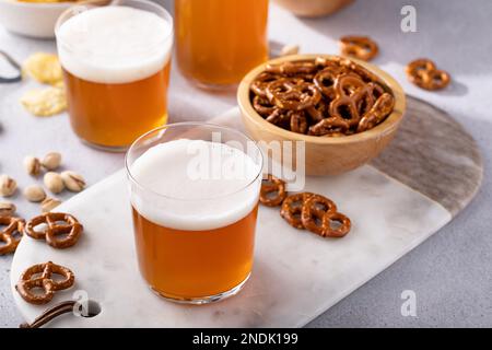 Traditional lager beer in variety of glasses with different snacks on the table on a sunny day Stock Photo