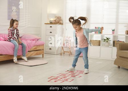 Cute little girls playing hopscotch at home Stock Photo