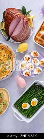 Easter brunch table with ham, quiche, hot cross buns and deviled eggs top view vertical banner Stock Photo