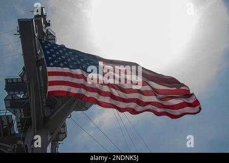 230215-N-FJ237-1148 SOUTH CHINA SEA (Feb. 15, 2023) The ensign flies aboard the aircraft carrier USS Nimitz (CVN 68). Nimitz Carrier Strike Group (NIMCSG) and Makin Island Amphibious Ready Group (MKI ARG), with embarked 13th Marine Expeditionary Unit (13th MEU), are conducting combined expeditionary strike force (ESF) operations, demonstrating unique high-end war fighting capability, maritime superiority, power projection and readiness. Operations include integrated training designed to advance interoperability between the two groups while simultaneously demonstrating the U.S. commitment to ou Stock Photo