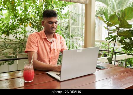 Serious Indian software developer working on laptop in coffeeshop Stock Photo