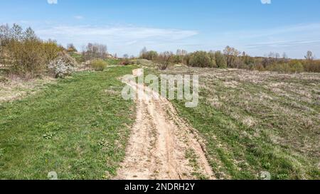 rural landscape with winding country road at sunny spring day. aerial view from flying drone. Stock Photo