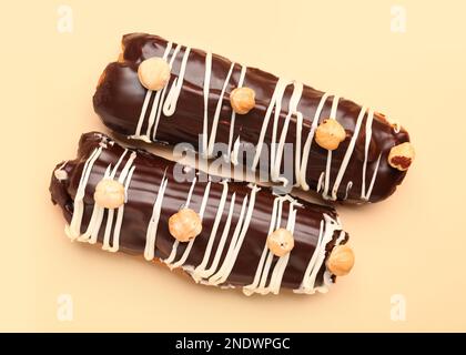 Delicious chocolate eclairs with hazelnuts on beige background Stock Photo