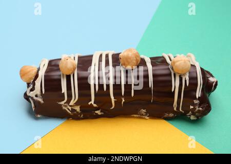 Delicious chocolate eclair with hazelnuts on colorful background Stock Photo