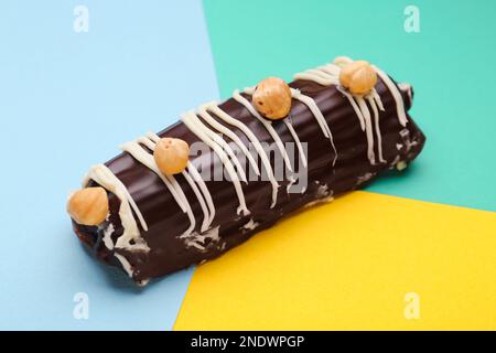 Delicious chocolate eclair with hazelnuts on colorful background Stock Photo