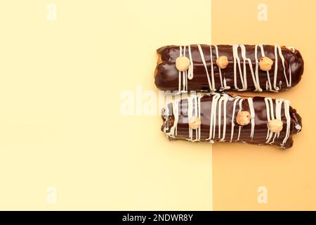 Tasty chocolate eclairs on yellow and orange background Stock Photo