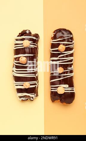 Tasty chocolate eclairs on yellow and orange background Stock Photo
