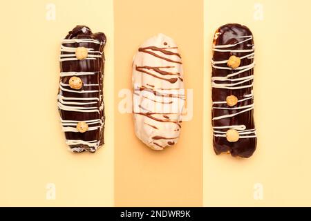 Tasty glazed eclairs on yellow and orange background Stock Photo