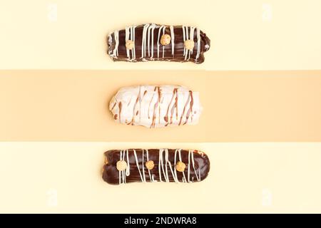 Tasty glazed eclairs on yellow and orange background Stock Photo