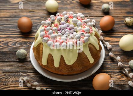 Composition with tasty Easter cake, eggs and willow branches on wooden background Stock Photo