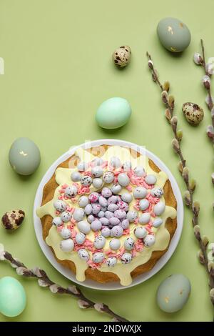 Composition with tasty Easter cake, eggs and willow branches on green background Stock Photo