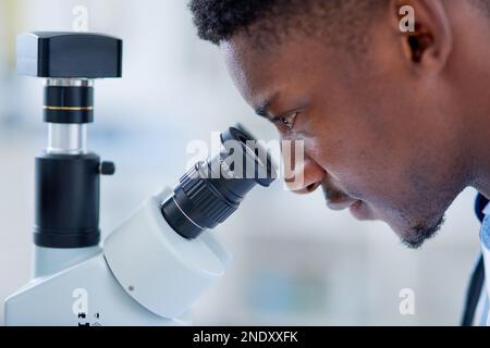 Looking through the eyes of the lens. a focused young male scientist looking at test samples through a microscope inside of a laboratory during the Stock Photo