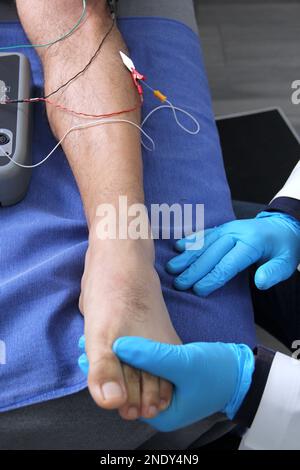 Electromyography in the lower limbs, graphic recording technique of the electrical activity produced by the tibial muscle performed by a specialist ne Stock Photo