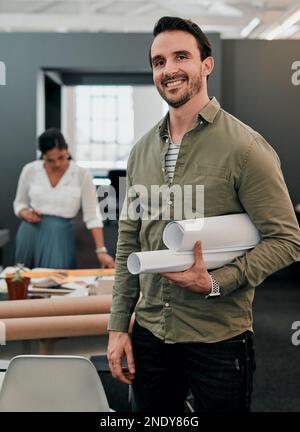 I always get extra exited when my blueprints are done. a young architect holding rolled up blueprints in an office. Stock Photo