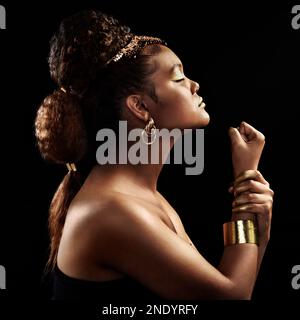 The strength and power of a Queen is unmatched. an attractive and elegantly dressed young woman posing against a dark background. Stock Photo