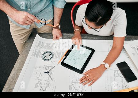 This is the part that needs a little more work. High angle shot of two unrecognizable architects using a digital tablet while working together in a Stock Photo