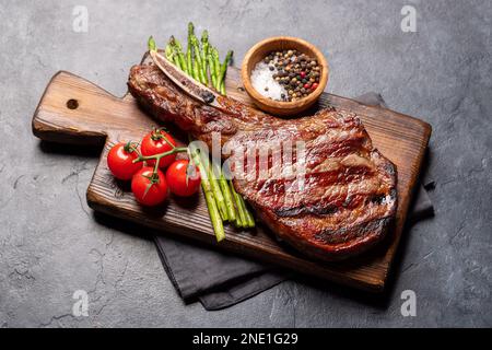 Medium rare grilled Tomahawk beef steak with asparagus on board Stock Photo