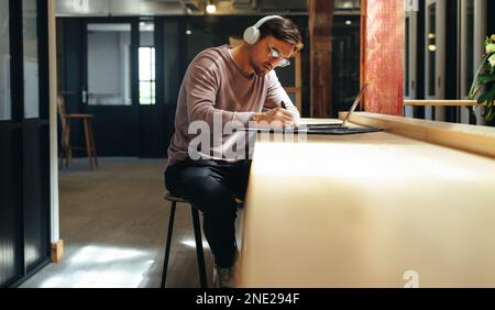 Professional web designer writing his progress in a clipboard. business man working on a design project in a coworking space. Creative designer doing Stock Photo