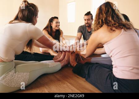 People doing the janusirsasana yoga pose while sitting in a circle. Group of happy people doing stretching exercises during a yoga session. Multicultu Stock Photo