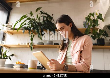 Non-binary trans woman using digital tablet in the kitchen at home. concept of gender fluidity Stock Photo