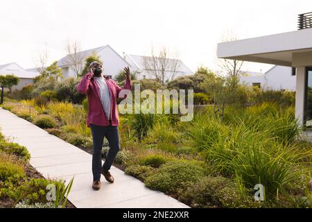 African american senior man smiling while talking on smartphone on the garden pathway. retirement senior lifestyle and living concept Stock Photo