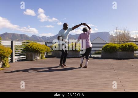 African american senior couple dancing together on the terrace at home. retirement senior lifestyle and living concept Stock Photo