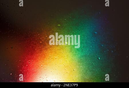 Dark glowing background with water drops with an explosion of rainbow colors. Stock Photo