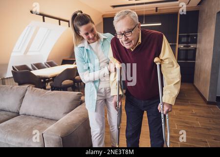 Nurse home caregiver is assisting old man at his home. Professional health support for elderly people. Stock Photo