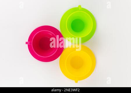 a multi-colored plastic cups and plates on a white background kitchen set Stock Photo