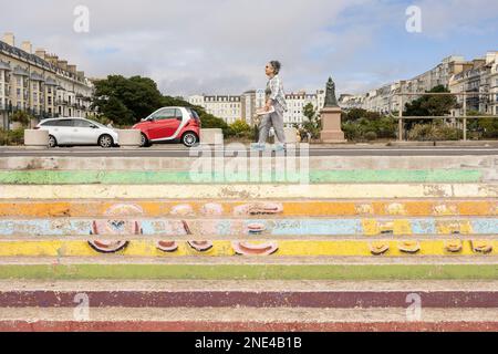 Hastings, united kingdom, 24, August 2022, elderly woman walking along hastings prom, passing some brightly coloured steps Stock Photo