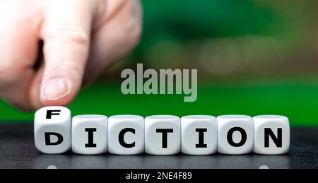 Hand turns dice and changes the word diction to fiction. Stock Photo