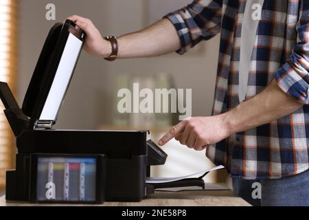 Man using modern multifunction printer in office, closeup Stock Photo