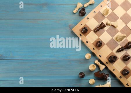 Flat lay composition of chess on light blue wooden table, space for text. Board game Stock Photo