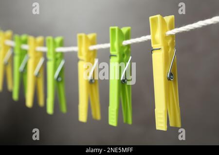 Colorful plastic clothespins on rope against grey background, closeup Stock Photo