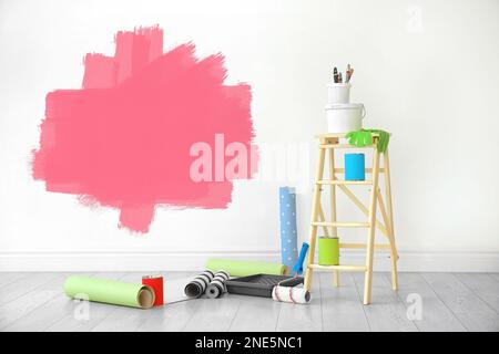 Set with decorator's tools and paint on floor near white wall Stock Photo