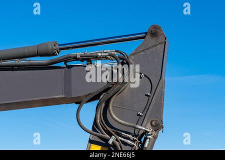 Part of excavator boom on blue sky background. Hydraulic mechanism close up. Stock Photo